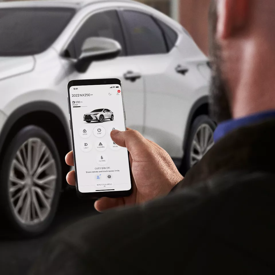 Owner using the Lexus app on a phone beside their SUV