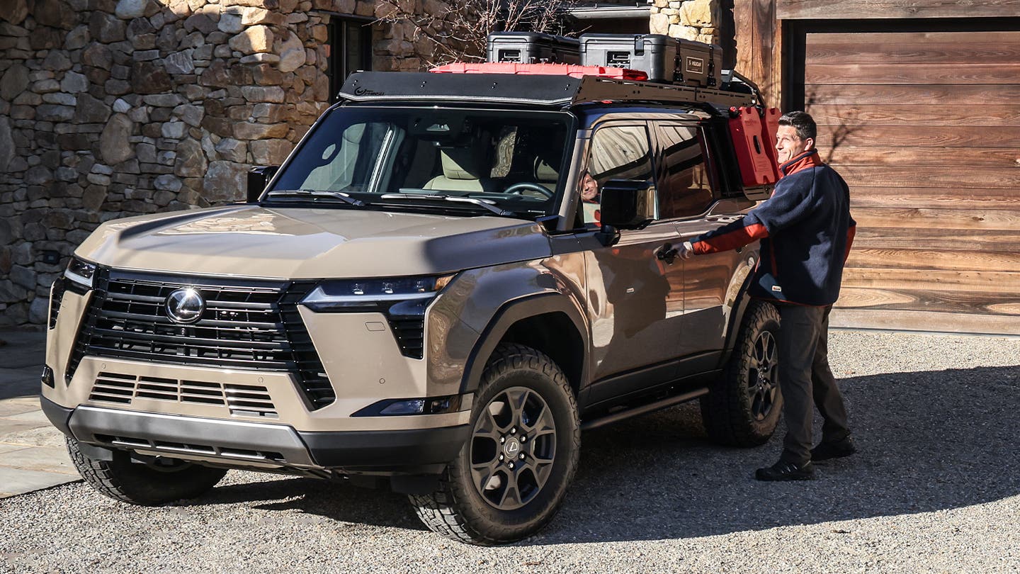 Owner loading gear onto the roof rack of a bronze Lexus GX outside a house