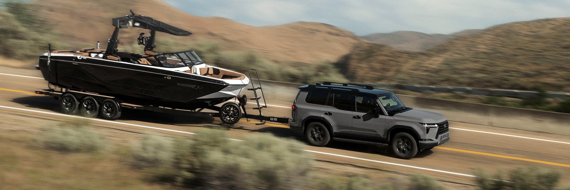 Lexus GX towing a boat along a highway through open country