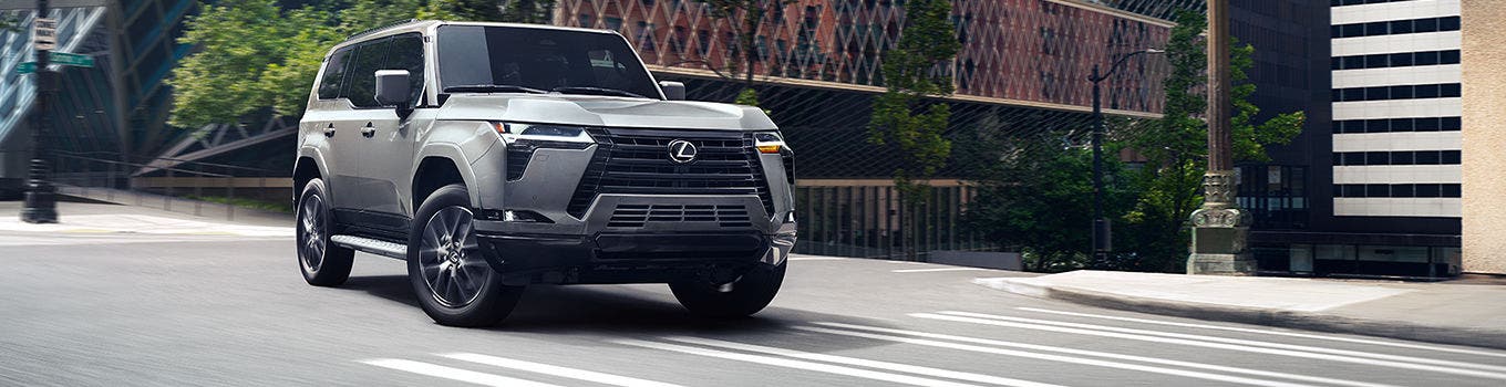 Lexus GX in silver crossing a city intersection