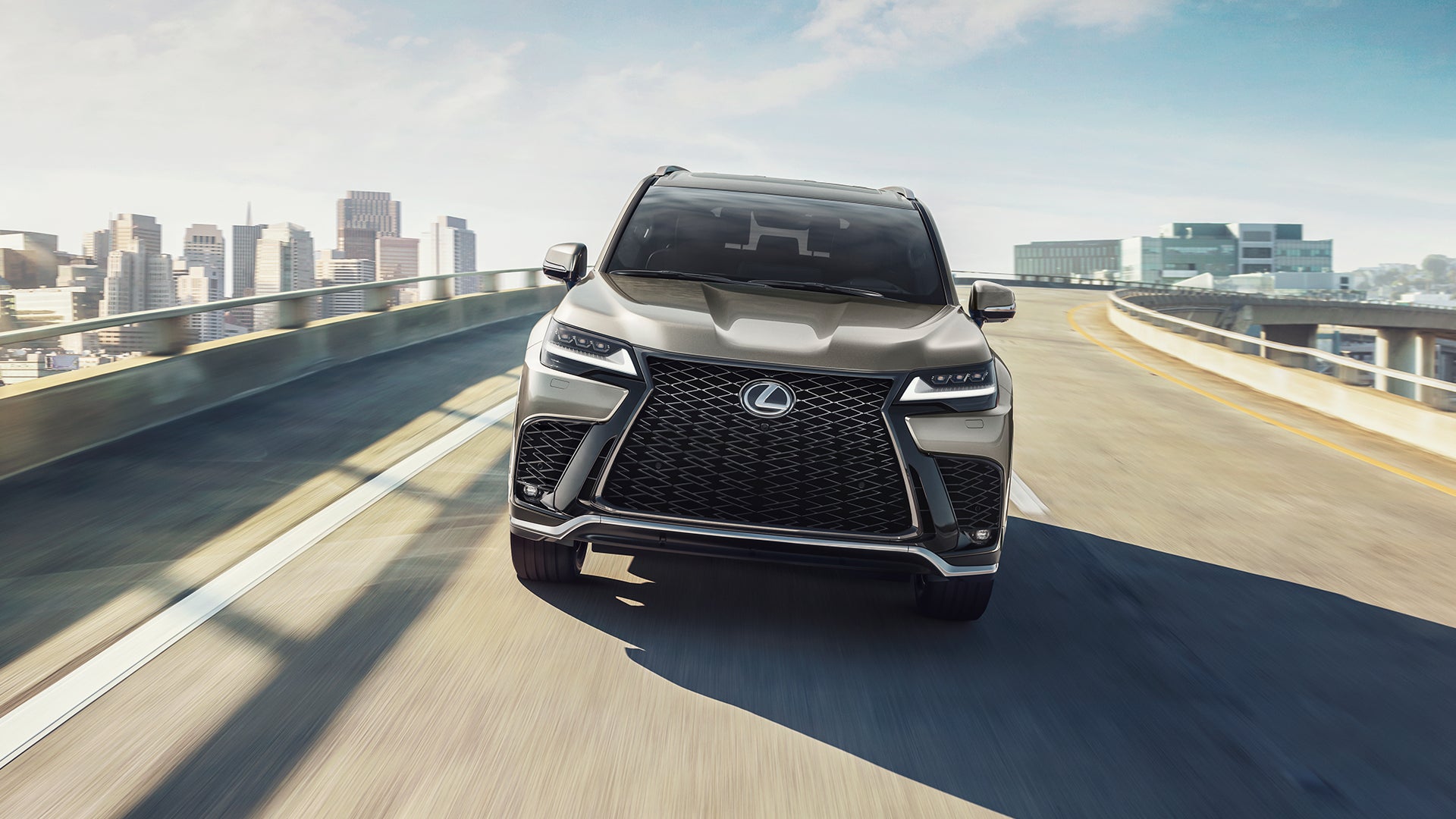 Lexus LX in gray on an elevated highway with a city skyline behind