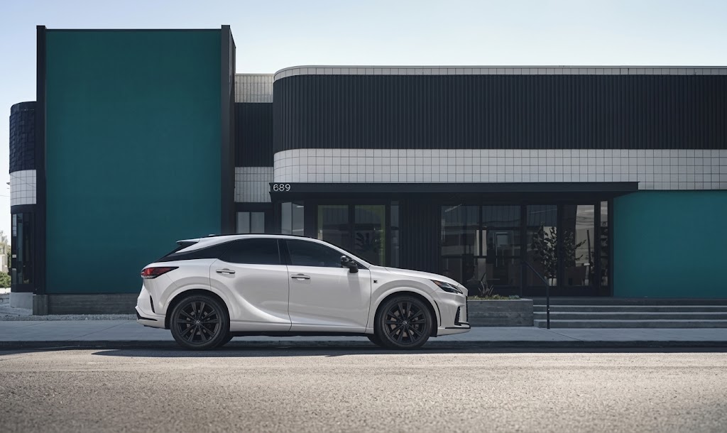 Lexus RX in white, side profile outside a modern teal and black building