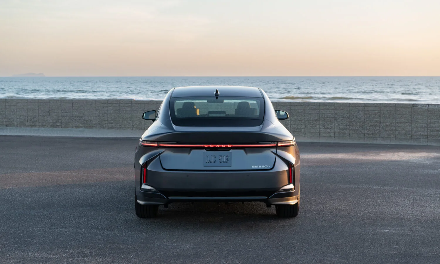 Lexus ES 350h in Cloudburst Gray from directly behind, full-width tail lamp lit
