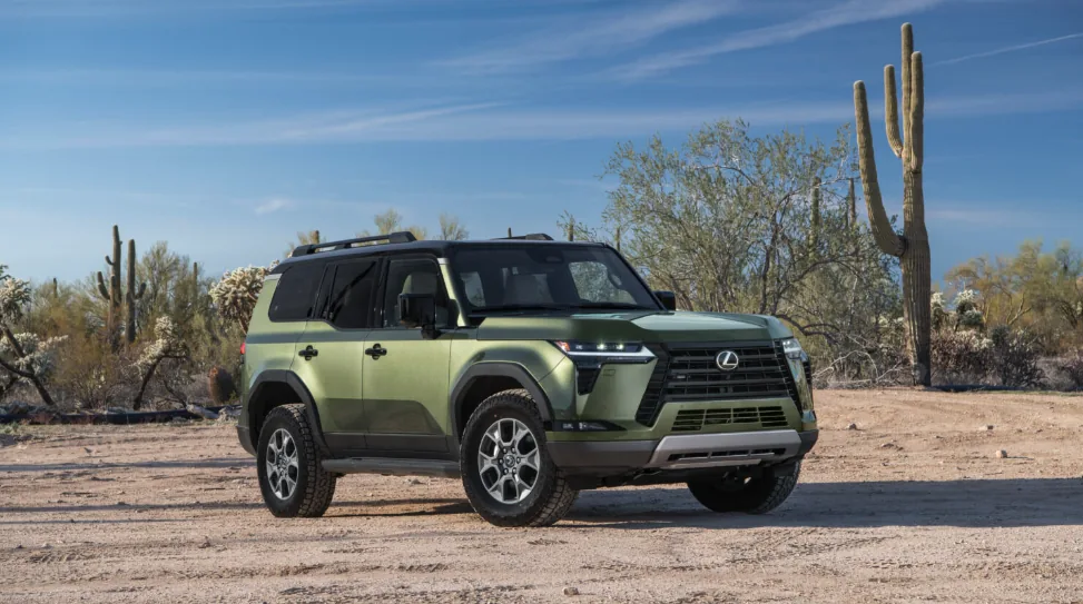 A green Lexus GX parked on desert ground among saguaro cactus