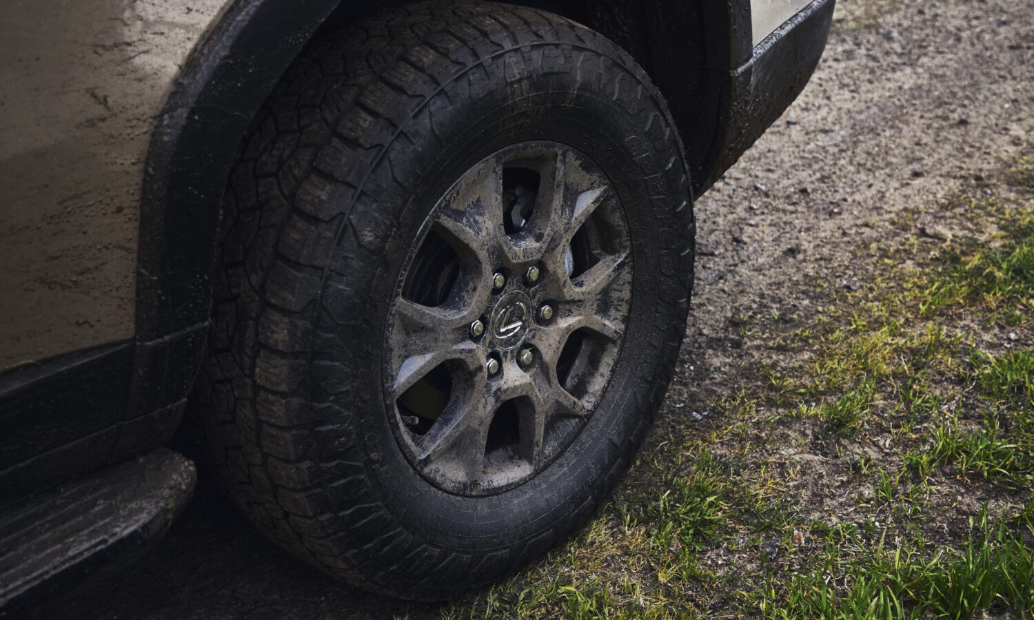 A close view of a dusty all-terrain tire and alloy wheel on a Lexus GX Overtrail parked on gravel