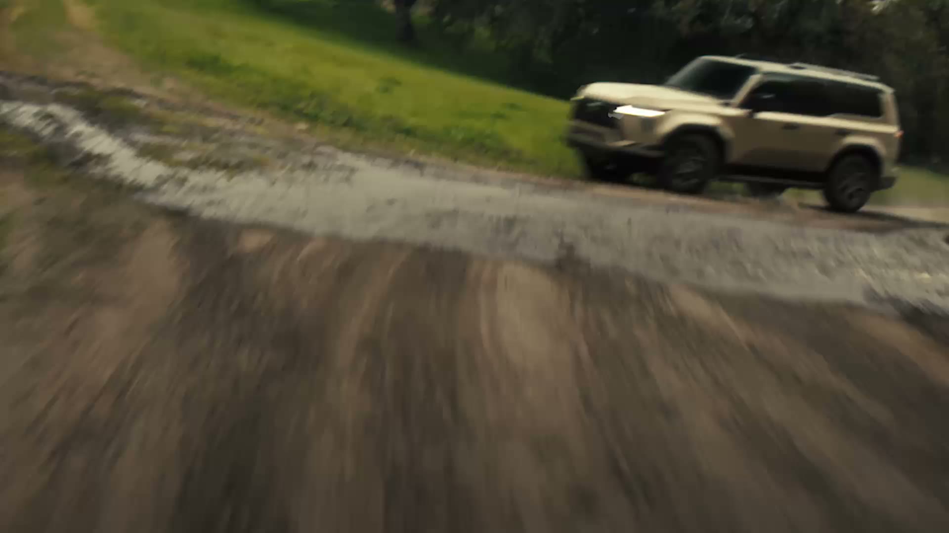 A sand-colored Lexus GX Overtrail driving on a dirt track, throwing up dust