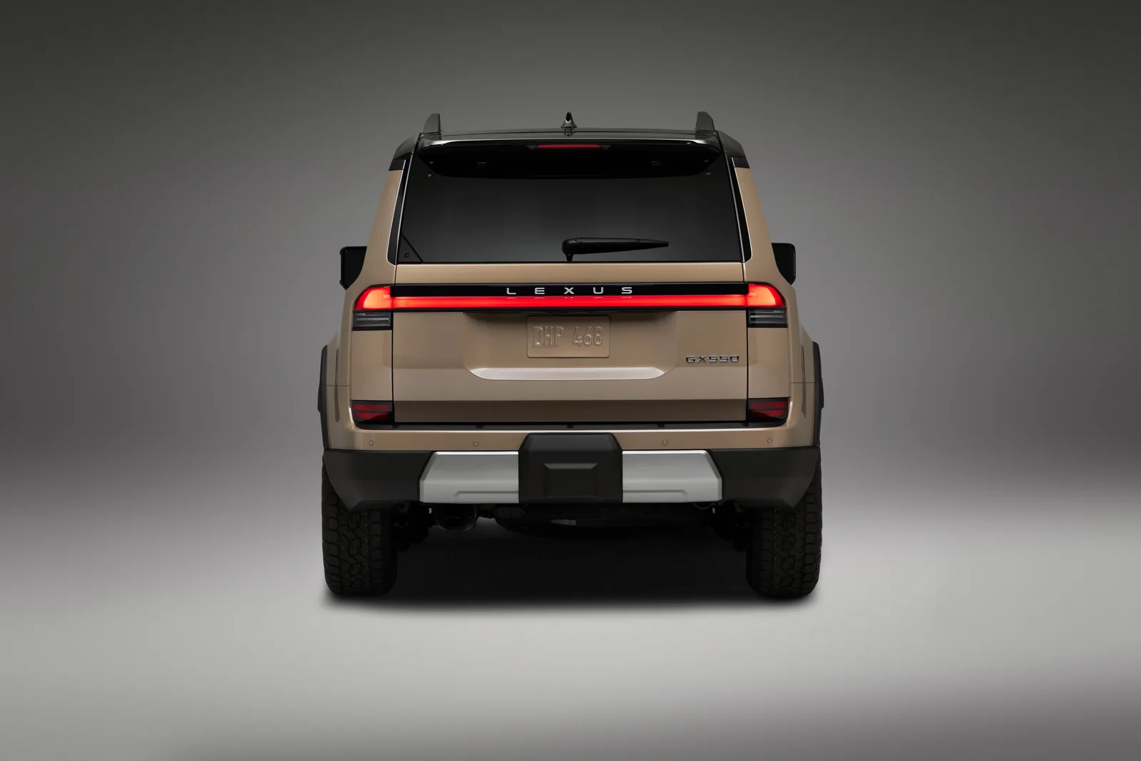 Lexus GX Overtrail in sand beige from directly behind, full-width tail lamp lit