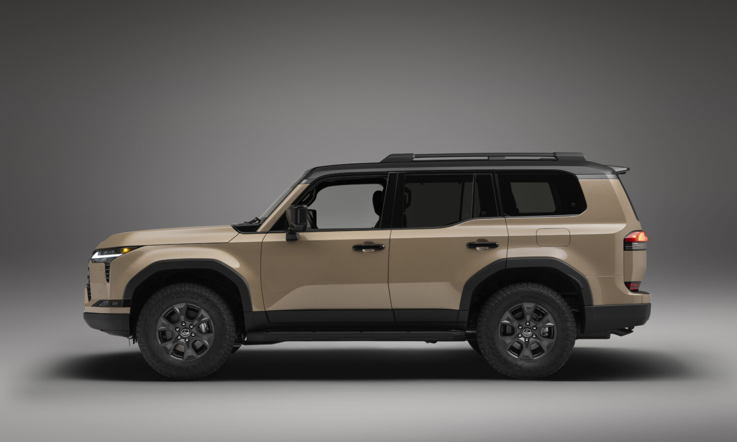 A sand-colored Lexus GX Overtrail in side profile against a plain background, showing its upright body-on-frame proportions