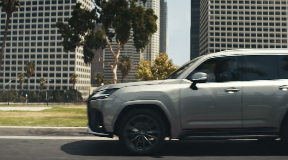 A silver Lexus LX F SPORT driving on a city street