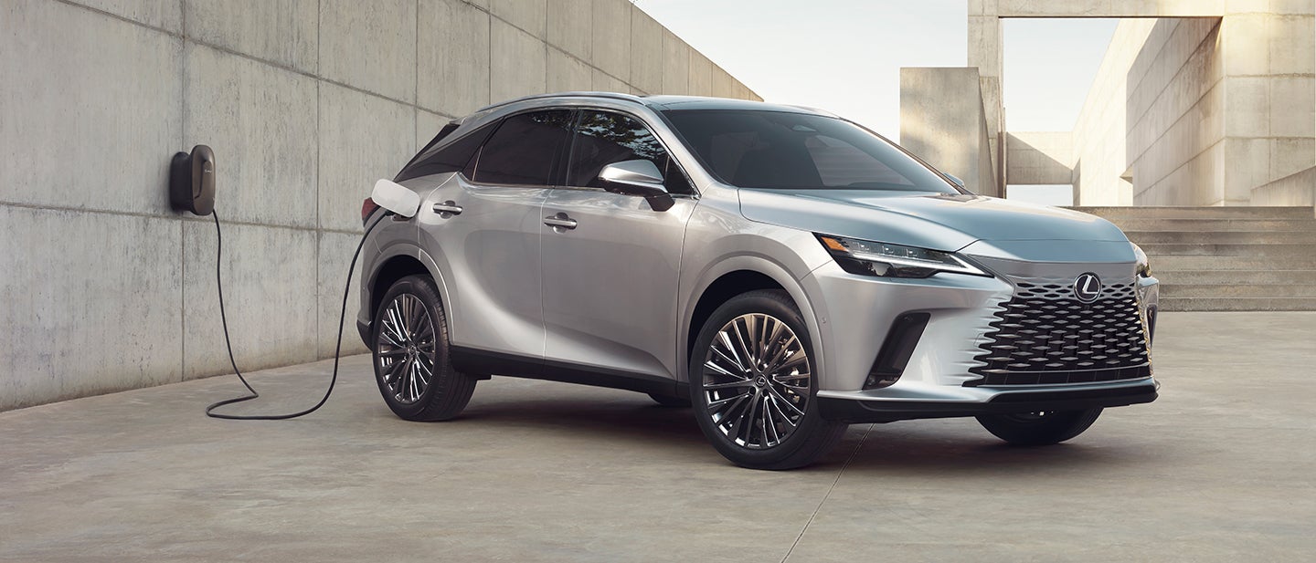 Lexus RX plug-in hybrid charging from a wall unit against bare concrete