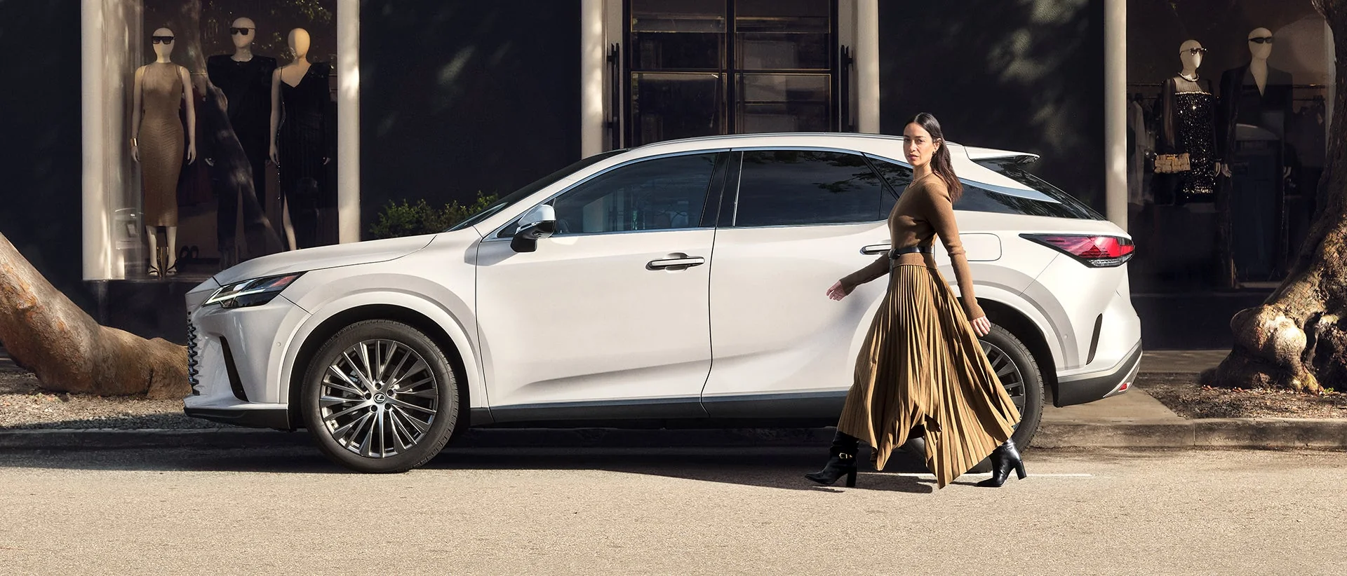 A white Lexus RX parked outside a boutique as a woman walks past the rear door