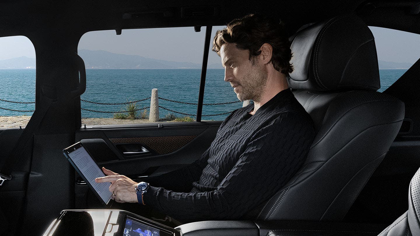 Passenger working on a tablet in the back of a Lexus courtesy shuttle