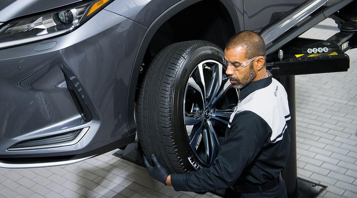 Lexus technician checking a wheel and tire with the car raised on the lift