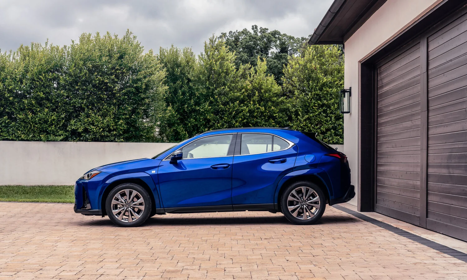 Lexus UX 300h F SPORT in blue, full side profile beside a hedge